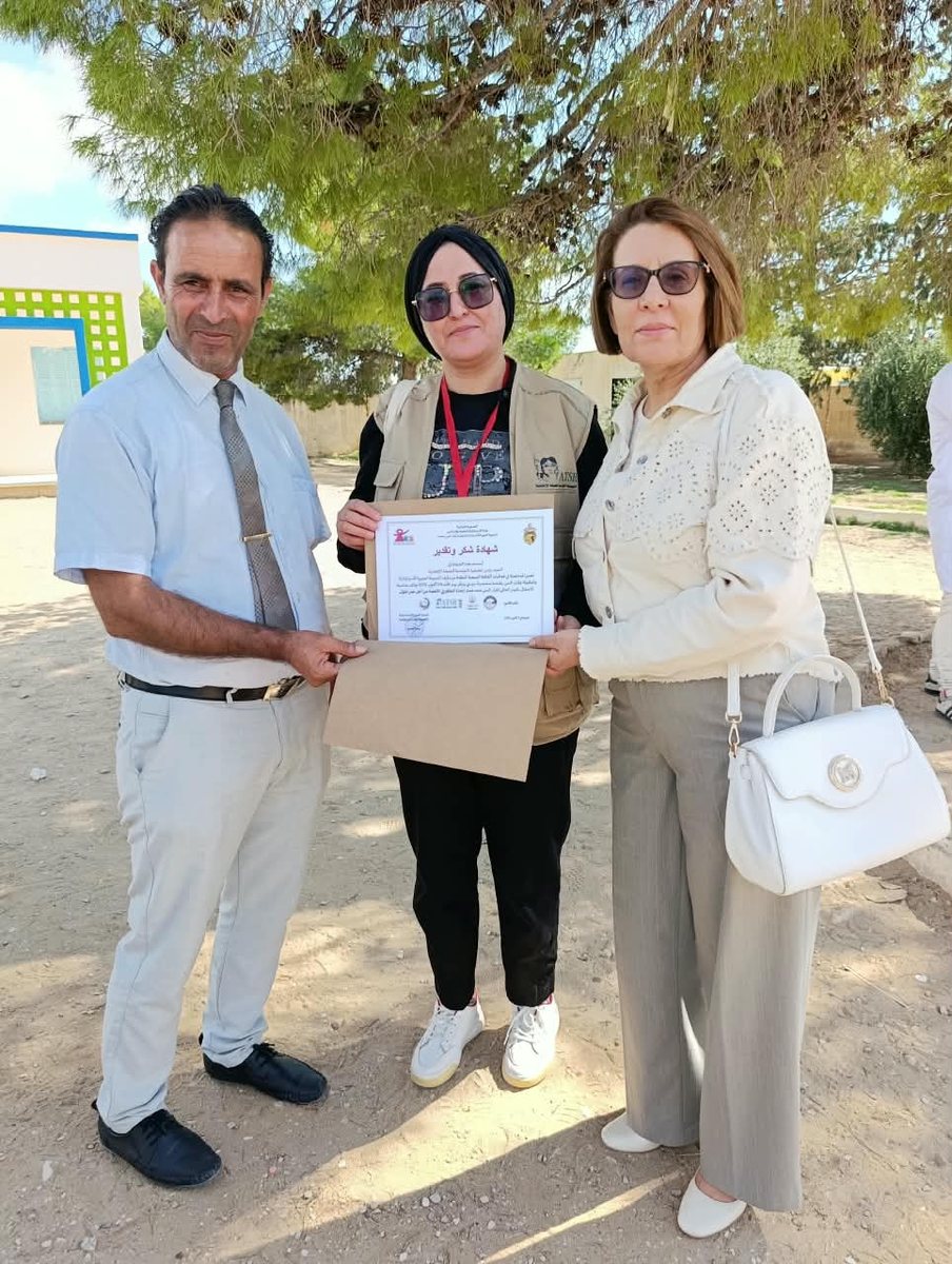 رجل وامرأتان يحملون شهادة مؤطرة في ساحة القافلة بسيدي بوبكر
