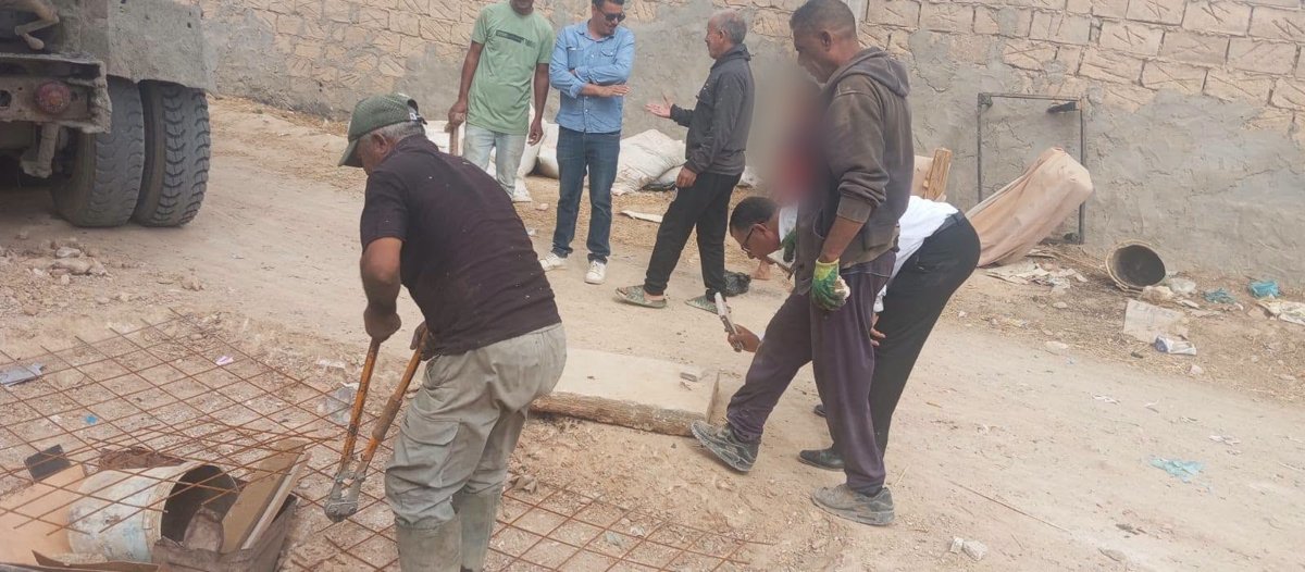 عمّال يقطعون شبكة حديد التسليح بمقصّ كبير أمام جدار حجري بمنطقة العقيلة، بحضور مسؤولين من بلدية قفصة
