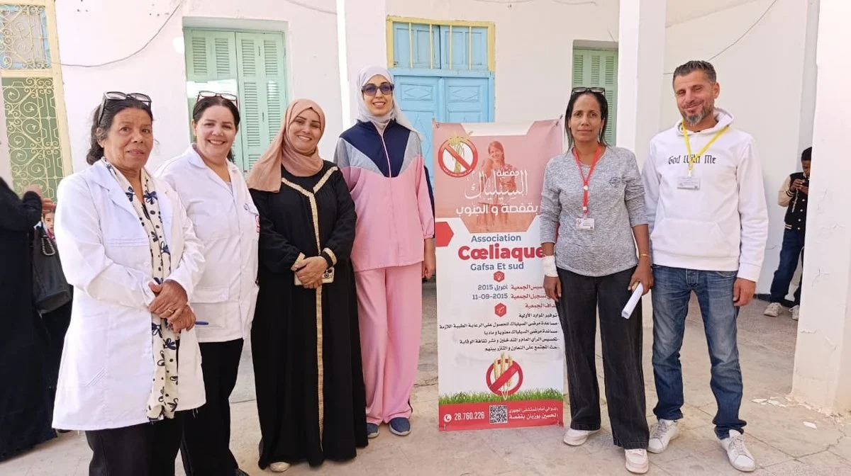 أعضاء من جمعية السيلياك بقفصة والجنوب وإطار طبي أمام لافتة الجمعية في ساحة مقرّها