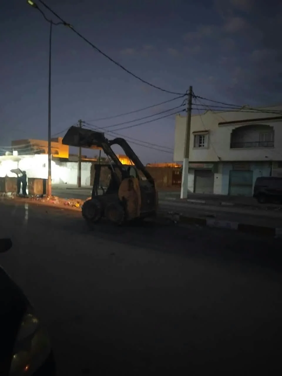 رافعة صغيرة وأعوان نظافة قرب حاويات فضلات عند الفجر في أحد شوارع قفصة