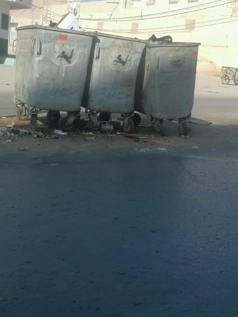 ثلاث حاويات معدنية كبيرة للفضلات على حافة شارع بقفصة وفضلات متناثرة حولها
