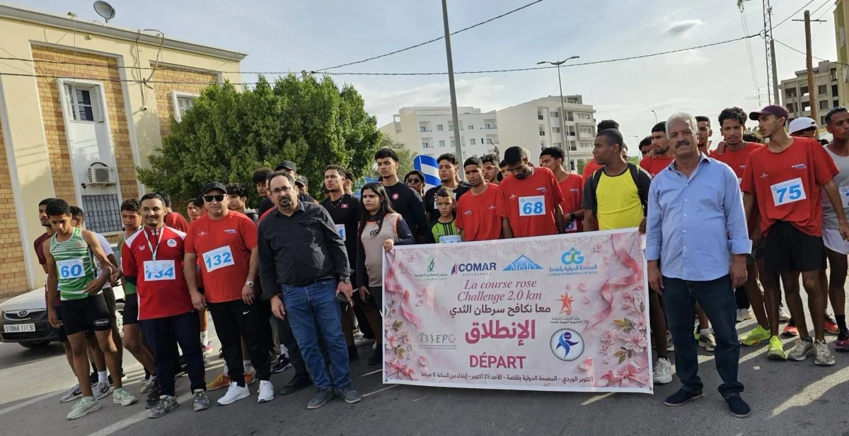 عدّاؤون ومسؤولون خلف لافتة الانطلاق لسباق La course rose أمام الإدارة الجهوية للديوانة بقفصة