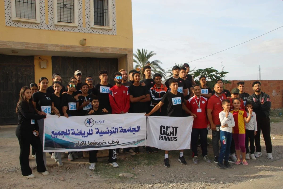 مشاركون يحملون لافتة الجامعة التونسية للرياضة للجميع ولافتة فريق GOAT Runners قبل السباق