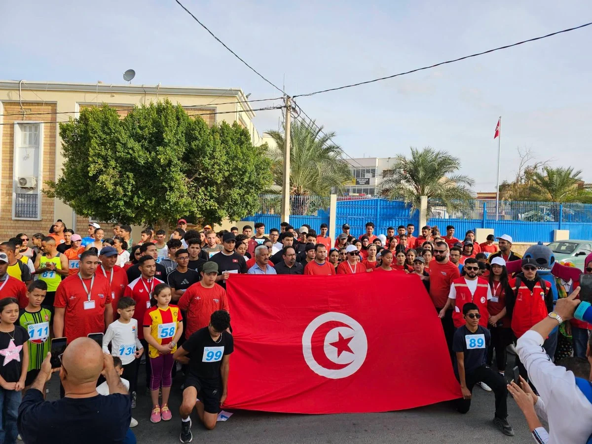 جمع من المشاركين والمنظمين يحملون علما تونسيا كبيرا قبل انطلاق السباق