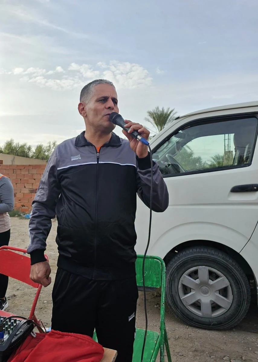 منشّط يتحدث عبر مضخّم الصوت بجانب حافلة صغيرة في موقع السباق