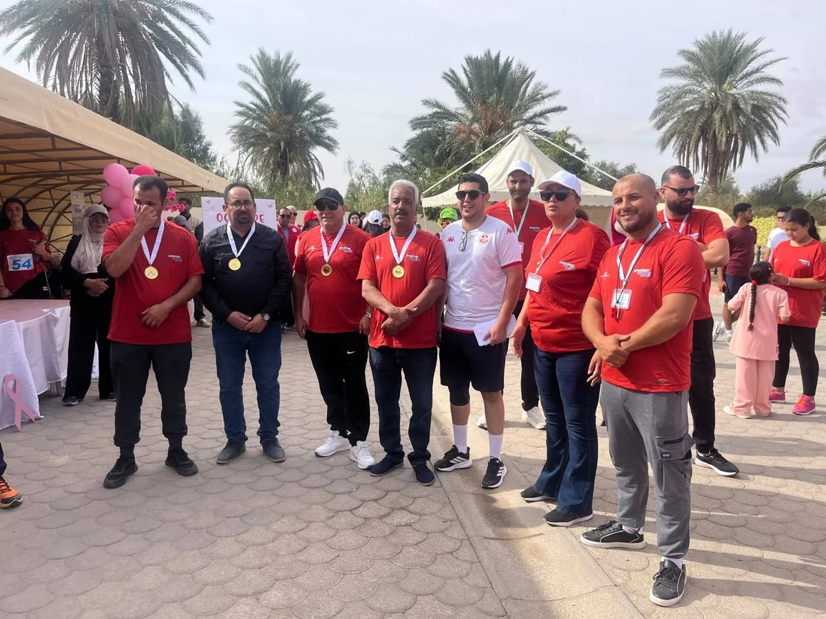 مشاركون ومنظمون يتقلّدون الميداليات في صورة جماعية بساحة التظاهرة