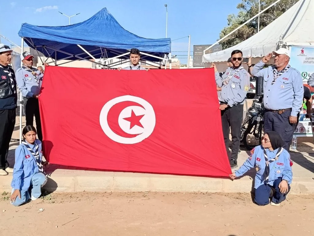 أفراد من الكشافة التونسية يمسكون علما وطنيا كبيرا قرب خيام تظاهرة التبرع بالأعضاء بقفصة