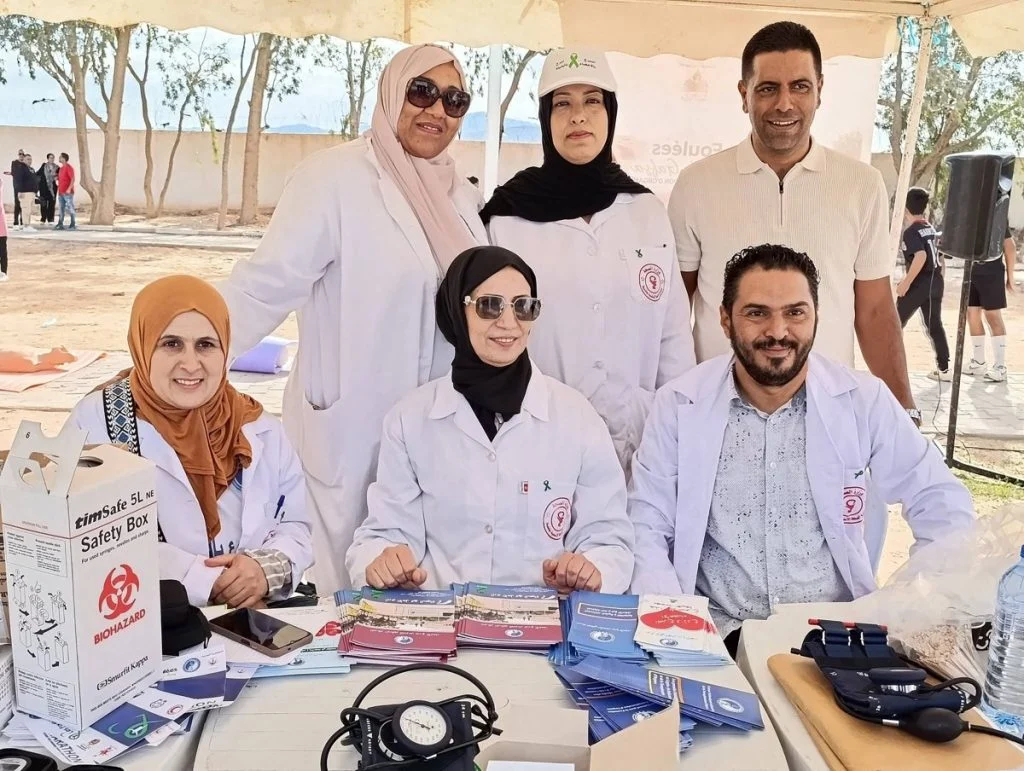 إطارات صحية بميدعات بيضاء أمام جهاز لقياس ضغط الدم ومطويات حول التبرع بالأعضاء بقفصة