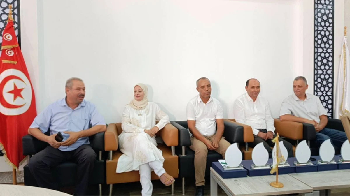 أساتذة وأستاذة يجلسون على أرائك جلدية قرب العلم التونسي وأمامهم مجسمات شهادات التقدير