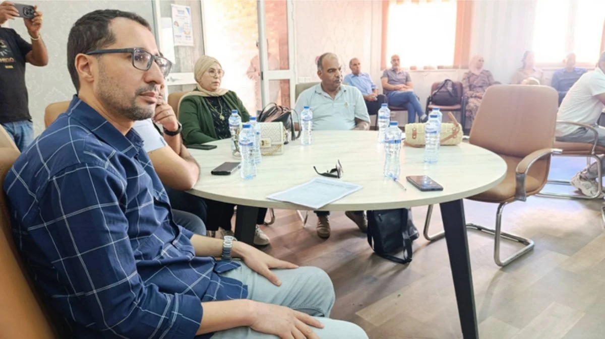 حاضرون يجلسون حول طاولة مستديرة عليها قوارير ماء خلال حفل التكريم