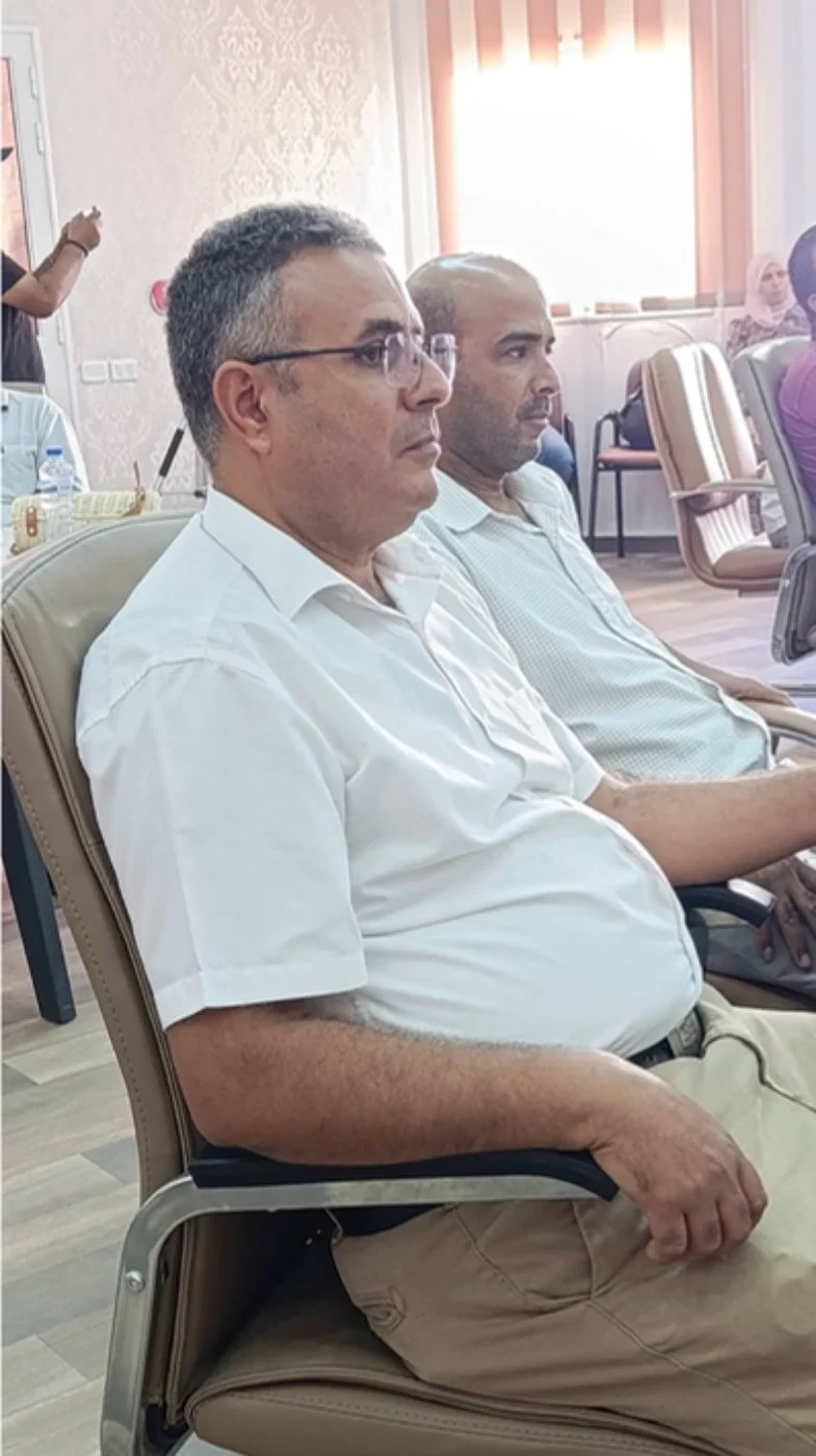 أستاذان يجلسان على كرسيين جلديين ويتابعان فقرات الحفل