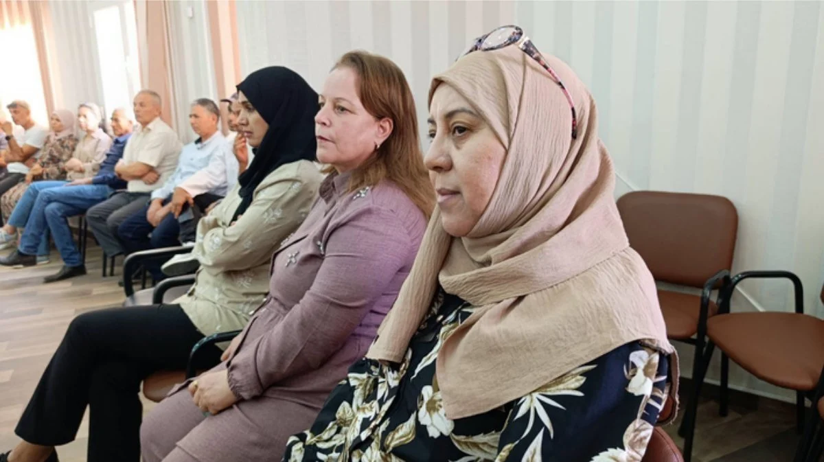 ثلاث حاضرات في الصف الأمامي يتابعن الحفل وخلفهن صف من الحاضرين