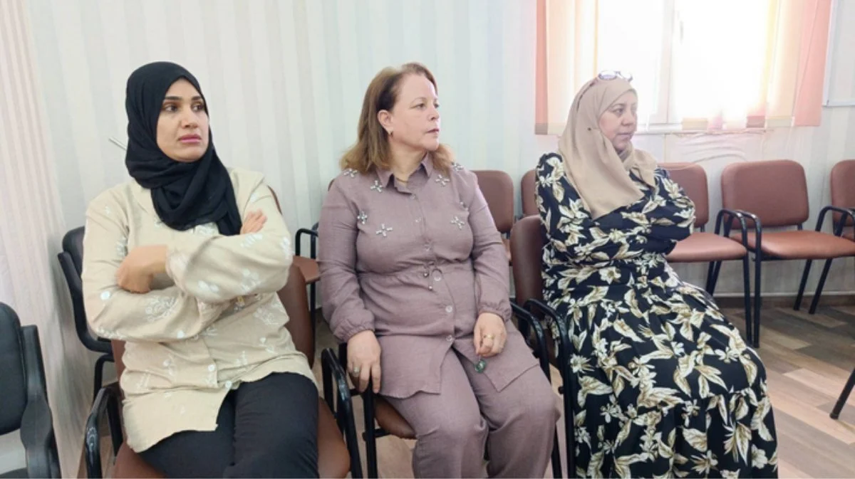 ثلاث سيدات جالسات على كراسٍ في قاعة الحفل يتابعن الكلمات