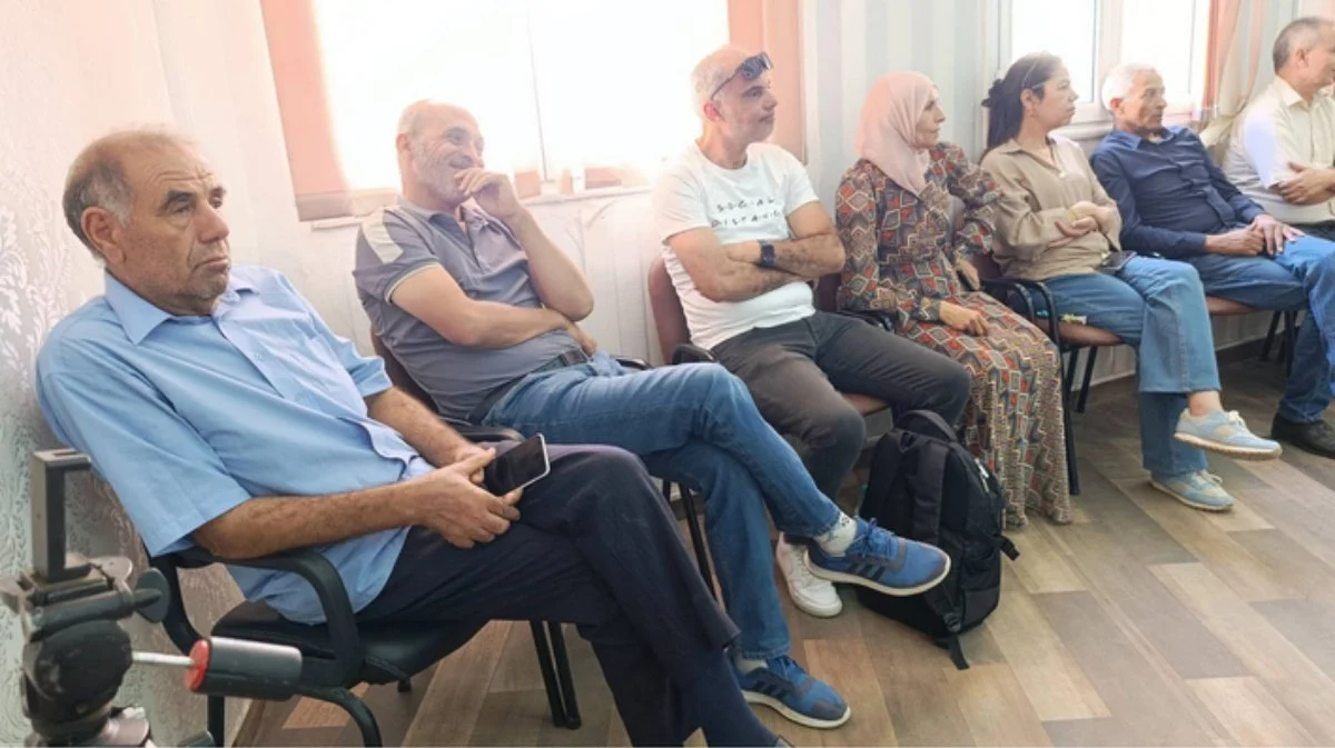 حاضرون جالسون على كراسٍ قرب النوافذ يستمعون خلال الحفل