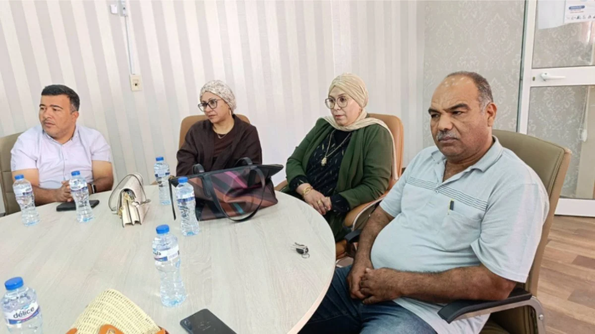 أربعة حاضرين حول طاولة مستديرة عليها قوارير ماء يتابعون الحفل