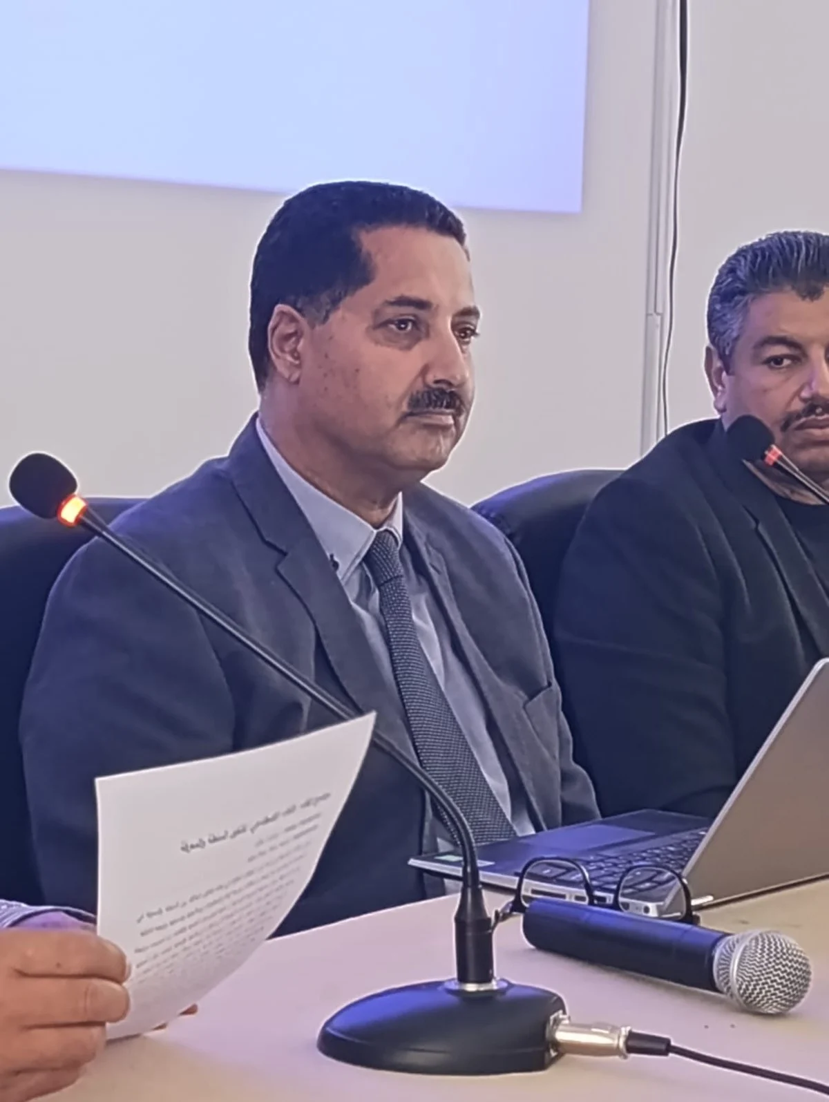 محاضر يتحدث أمام الميكروفون وبيده ورقة خلال اللقاء الفكري حول الذكاء الاصطناعي بالمعهد العالي بقفصة