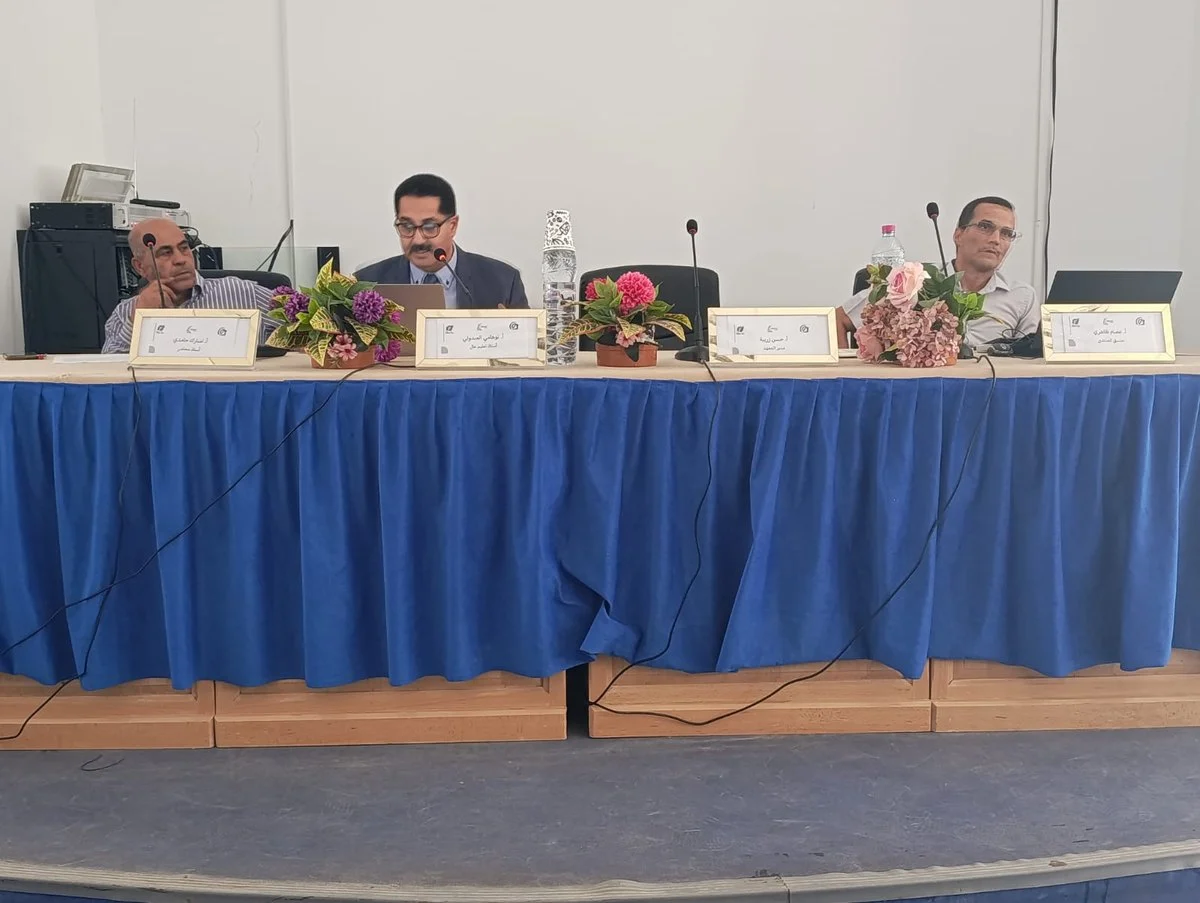 منصة المحاضرين وطاولة مزيّنة بالورود في مدرج المعهد العالي للدراسات التطبيقية في الإنسانيات بقفصة