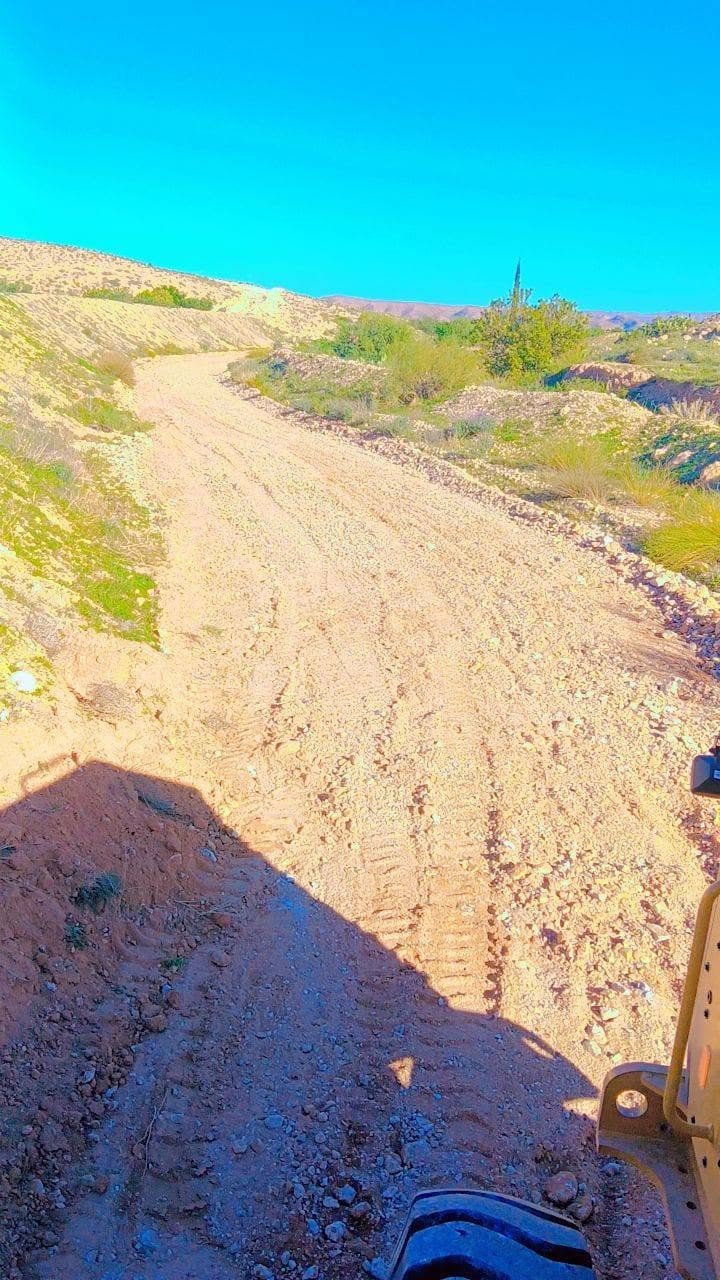 مسلك حصوي صاعد بين تلال تكسوها نباتات خضراء بعد مسحه
