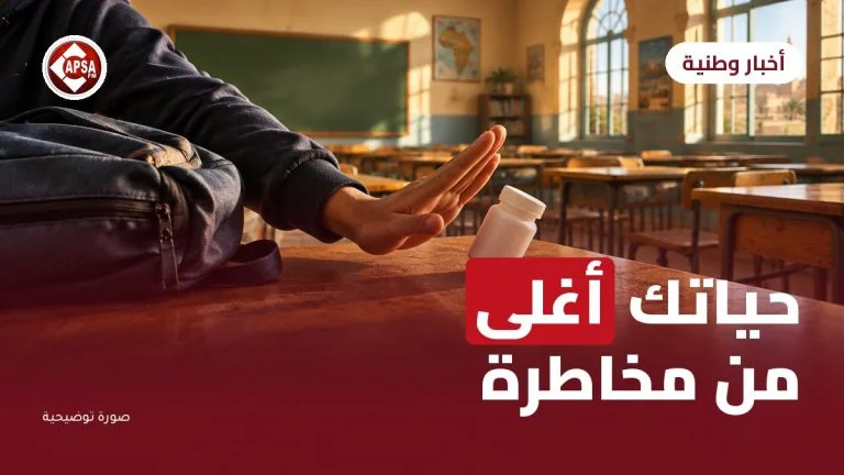 يد تلميذ تدفع علبة دواء بيضاء على طاولة في قسم مدرسي، مع عنوان «حياتك أغلى من مخاطرة» وشعار راديو كابصا اف ام (صورة توضيحية)