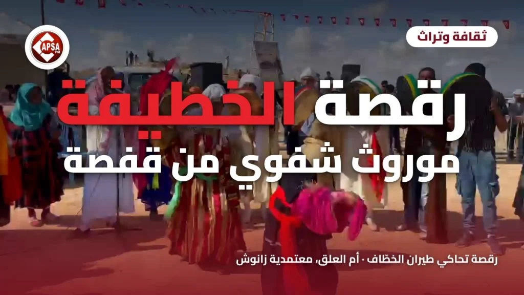 راقصة بمحرمة وردية وحزام أحمر أمام عازفي البندير والقصبة على ساحة رملية بأم العلق، مع عنوان «رقصة الخطيفة موروث شفوي من قفصة» وشعار راديو كابصا اف ام