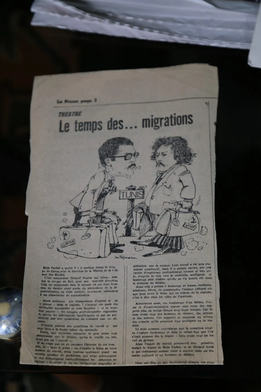 Coupure du journal La Presse intitulée Le temps des migrations, avec une caricature de deux hommes portant des valises marquées Gafsa et Le Kef devant un panneau Tunis