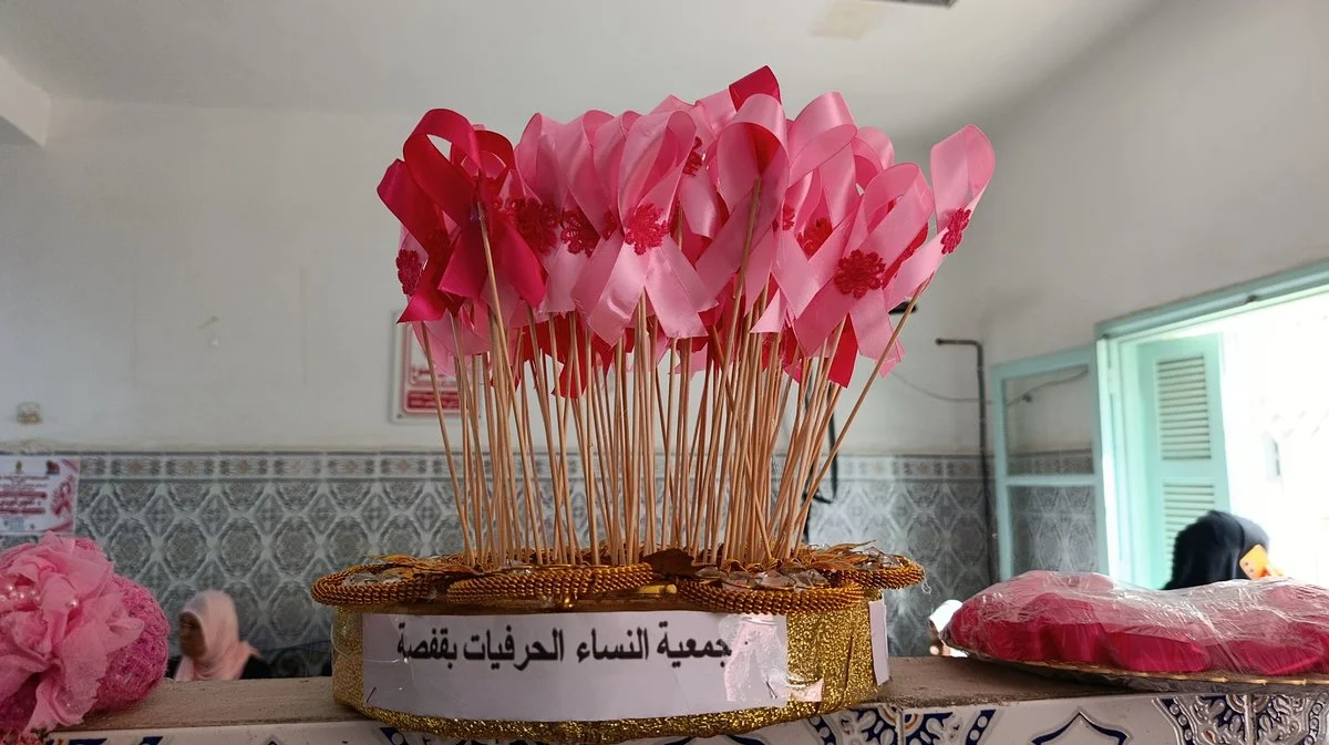 أشرطة وردية على أعواد في سلة تحمل اسم جمعية النساء الحرفيات بقفصة بمناسبة أكتوبر الوردي
