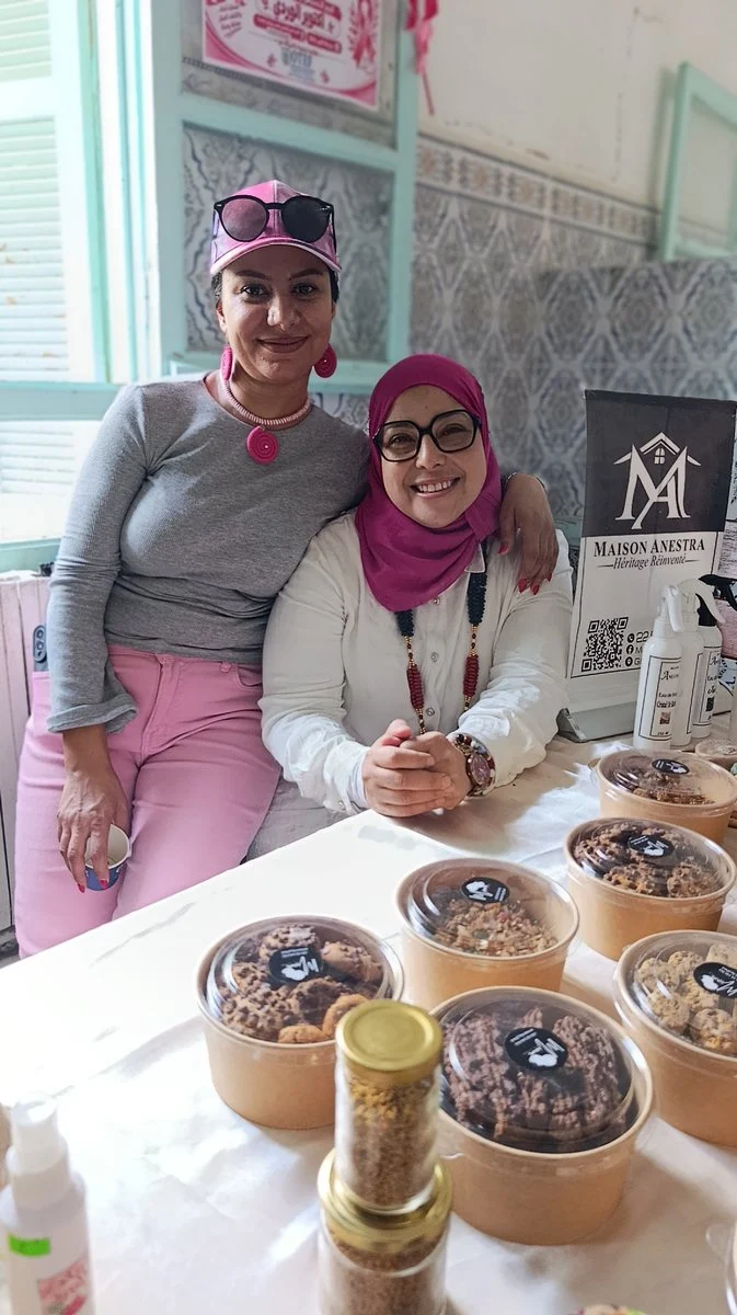 مشاركتان أمام طاولة منتوجات طبيعية في معرض جمعية النساء الحرفيات بقفصة