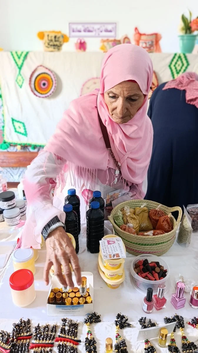 حرفية ترتّب منتوجات طبيعية على طاولة المعرض بالمستشفى الجامعي الحسين بوزيان