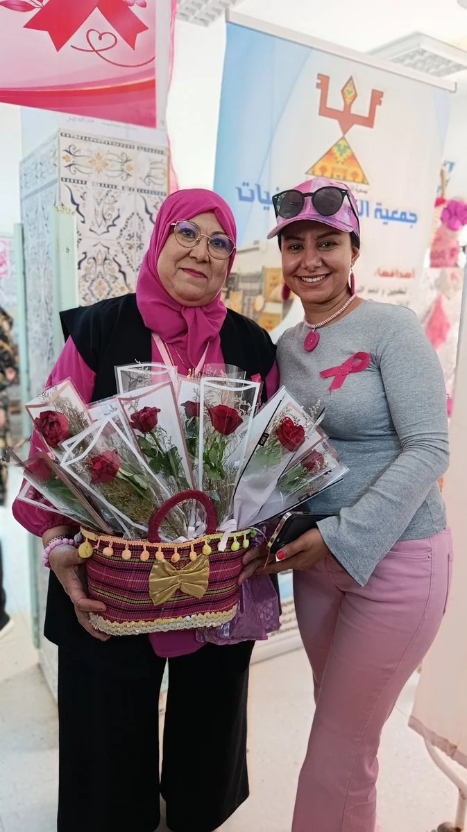 مشاركتان تحملان سلة ورود حمراء في اليوم التحسيسي لأكتوبر الوردي بقفصة