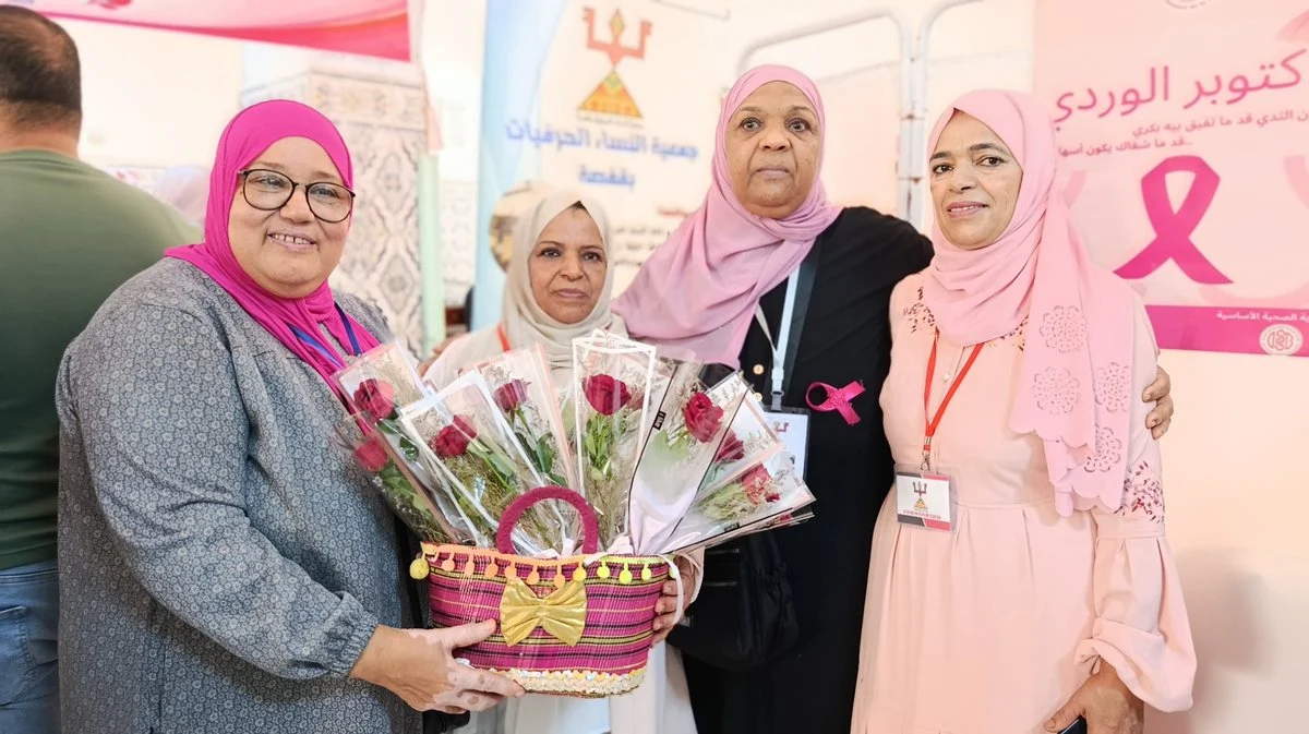 مشاركات يحملن سلة ورود حمراء أمام ملصق أكتوبر الوردي بالمستشفى الجامعي بقفصة