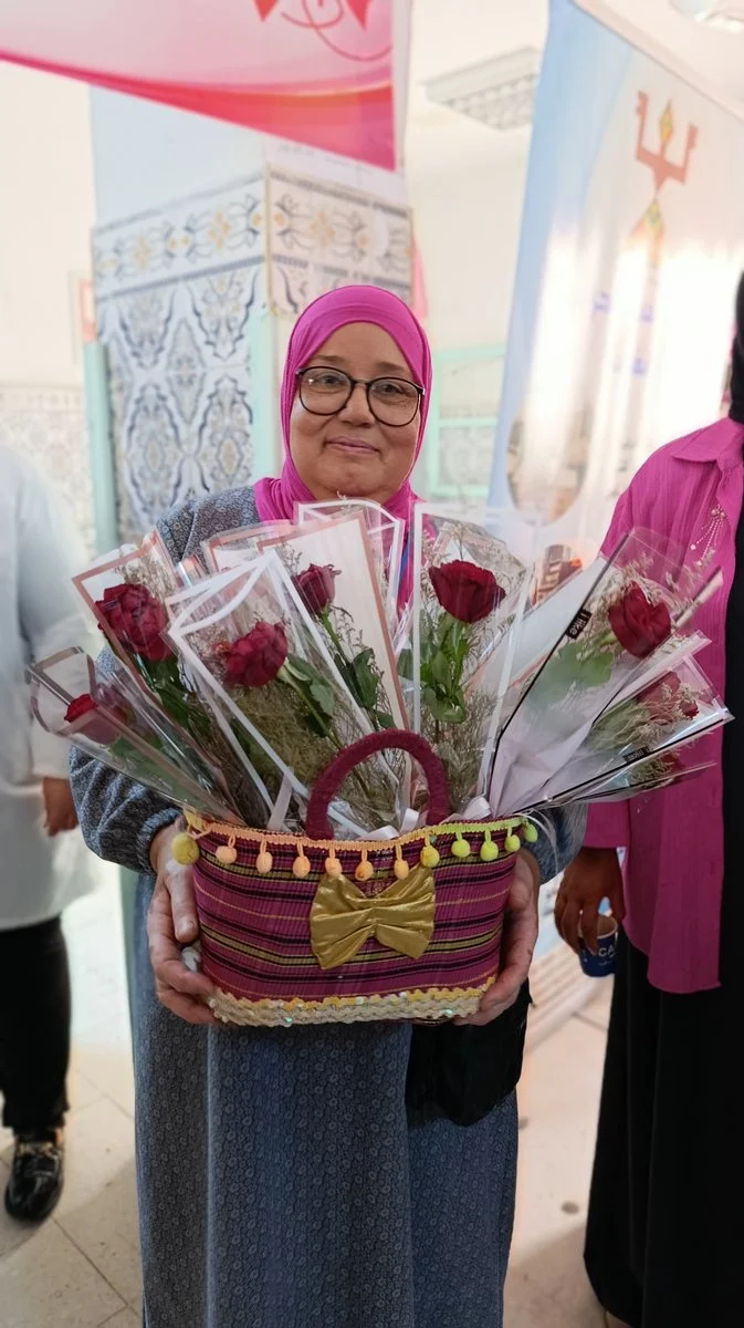 مشاركة تحمل سلة ورود حمراء في فضاء العيادات الخارجية بالمستشفى الجامعي بقفصة