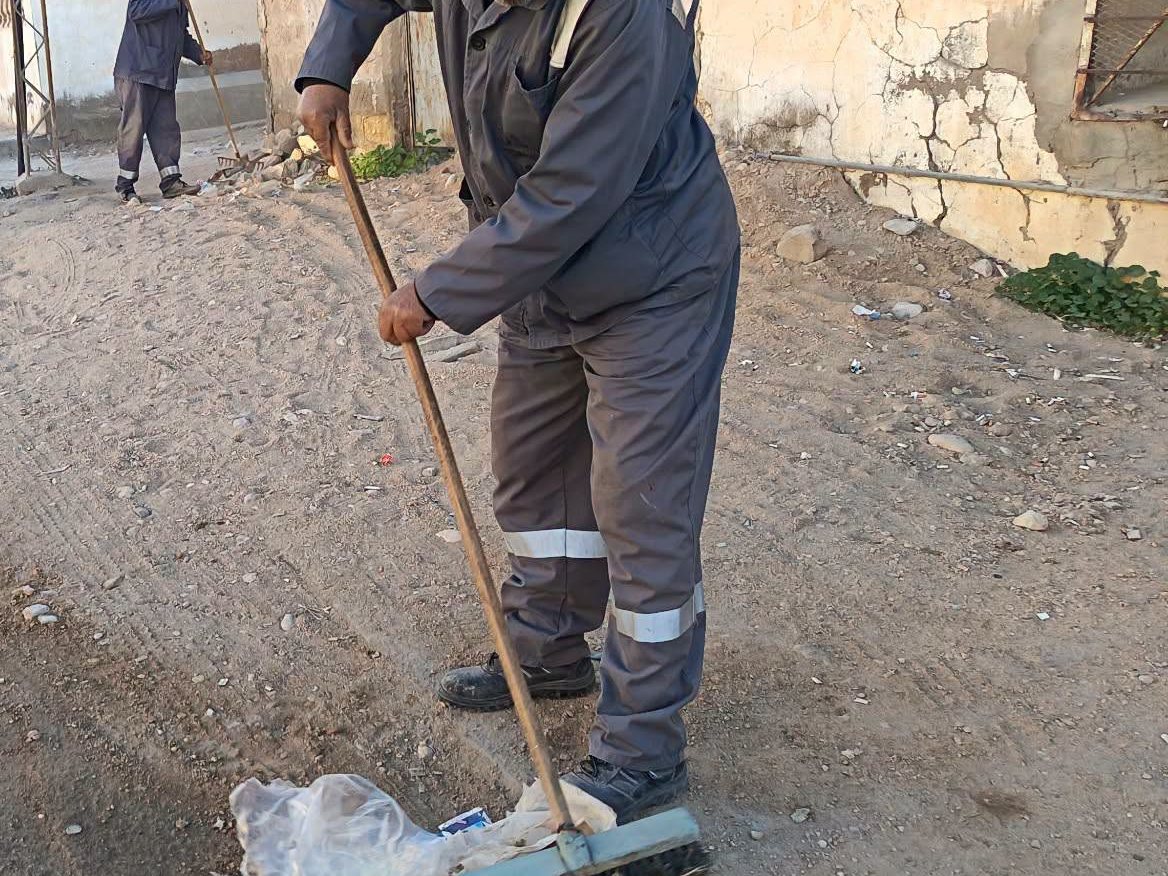 عون نظافة يكنس أكياسا بلاستيكية على حافة طريق معبّد بأم العرائس