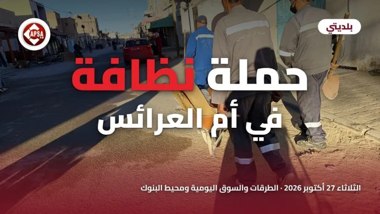 أعوان بلدية أم العرائس يدفعون عربة يدوية في شارع مشمس، مع عنوان «حملة نظافة في أم العرائس» وشعار راديو كابصا اف ام