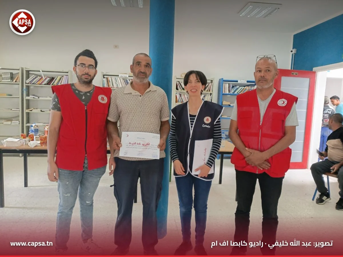 رجل بقميص بيج يحمل شهادة المشاركة في دورة الإسعافات الأولية بين أعضاء الفرع المحلي