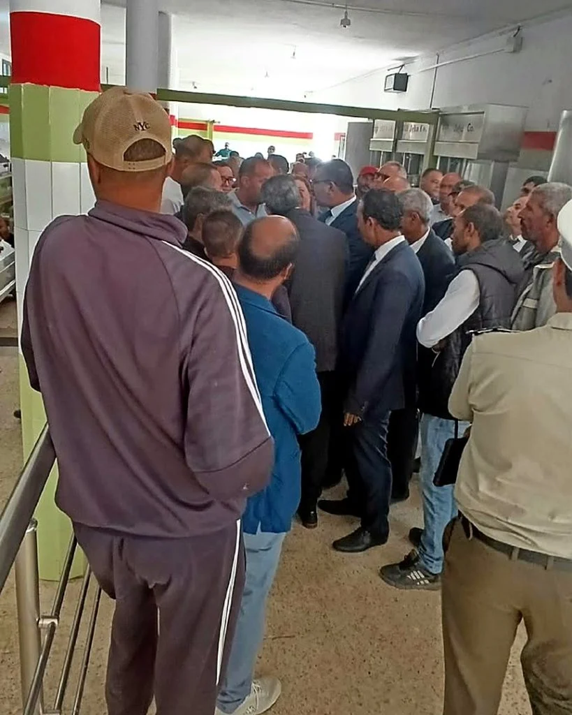 جمع من الفلاحين والمسؤولين داخل قاعة بأعمدة حمراء وخضراء خلال افتتاح الموسم بسيدي بوبكر