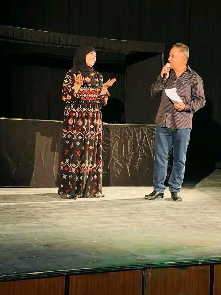 امرأة بلباس تقليدي مطرّز ورجل يحمل مصدحا على ركح دار الثقافة بأم العرائس خلال الافتتاح