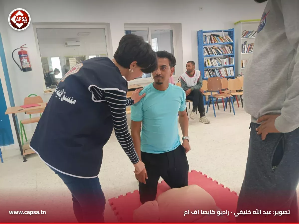 منسّقة الدورة توجّه مشاركا جاثيا أمام دمية الإنعاش إلى الوضعية الصحيحة للمسعف