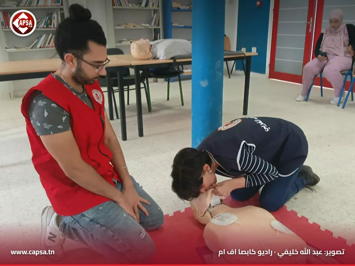 متطوعة تُظهر حركة فتح مجرى التنفس على دمية تدريب أمام متطوع جاثٍ من الهلال الأحمر